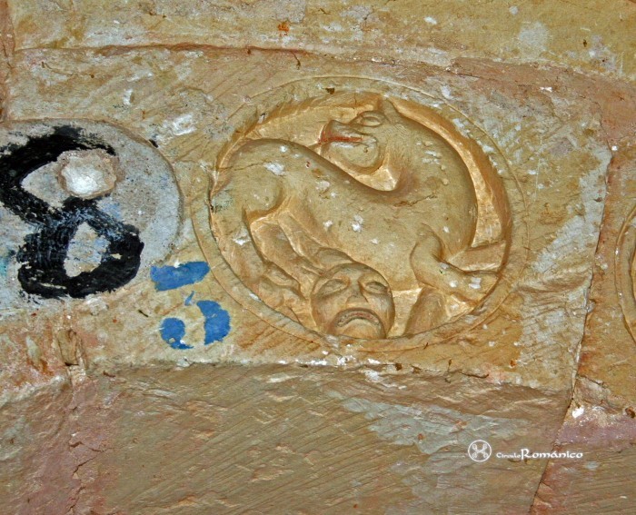 Almendres. San Millán Abad. Arquivolta interior: Roleo con cabeza humana bajo perro 