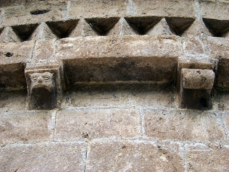 Llo. Sant Fructuós. Canecillos: cabeza monstruosa y rollo